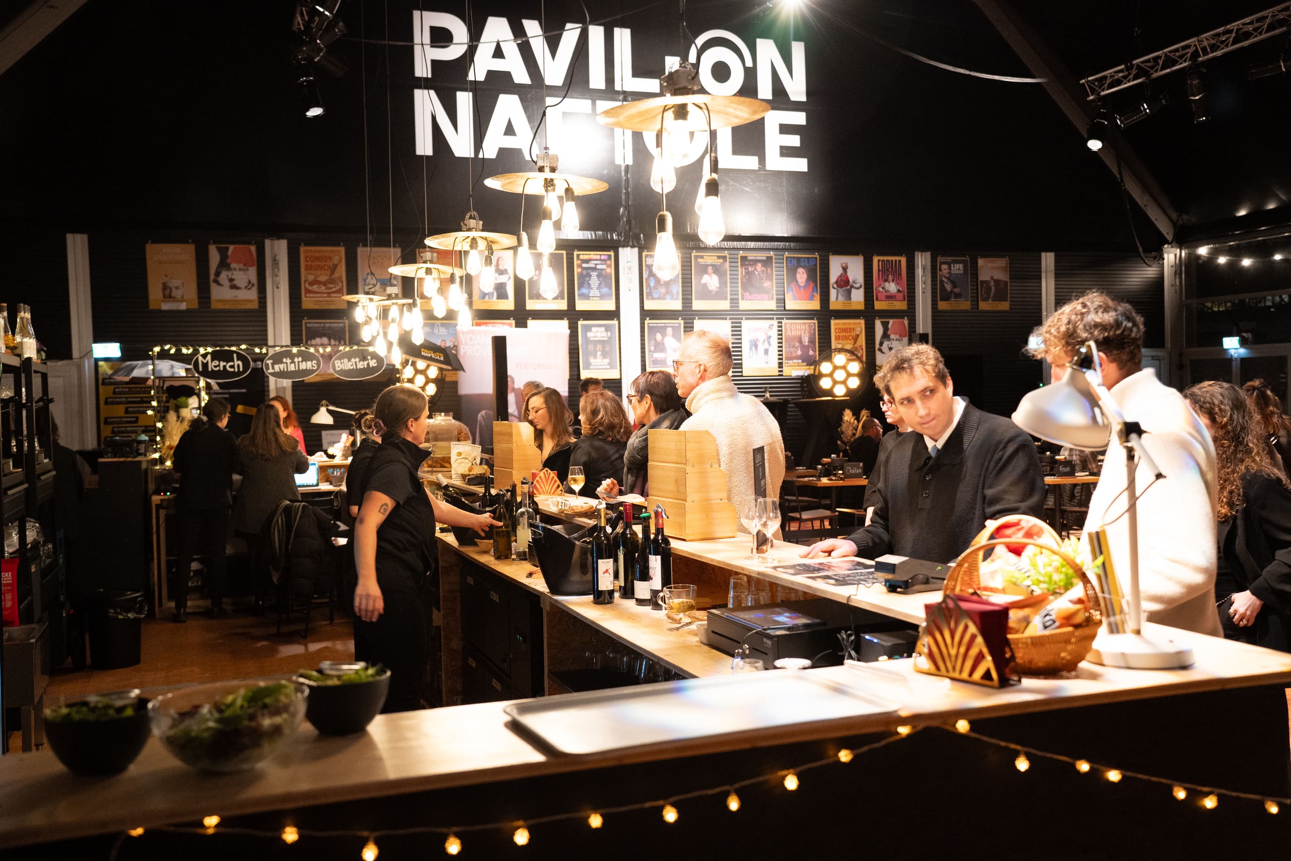 Le foyer du Pavillon un soir de spectacle, avec le mur d'affiches de la saison